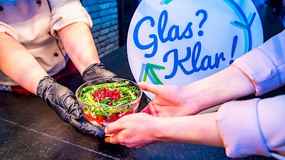Glasschale mit Salat wird überreicht