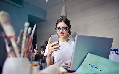Junge Malerin schaut auf ihr Handy