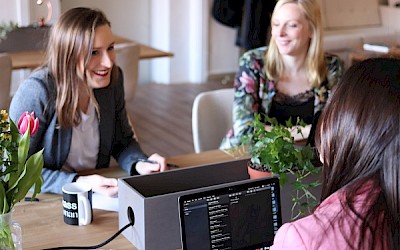 Junge Frauen sprechen an Schreibtisch miteinander