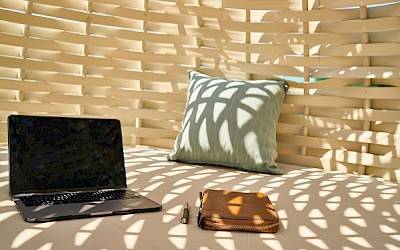 Laptop und Notizbuch lieben im Schatten auf Daybed